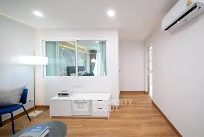 Modern living room with wooden flooring, stylish furniture, and air conditioning unit.