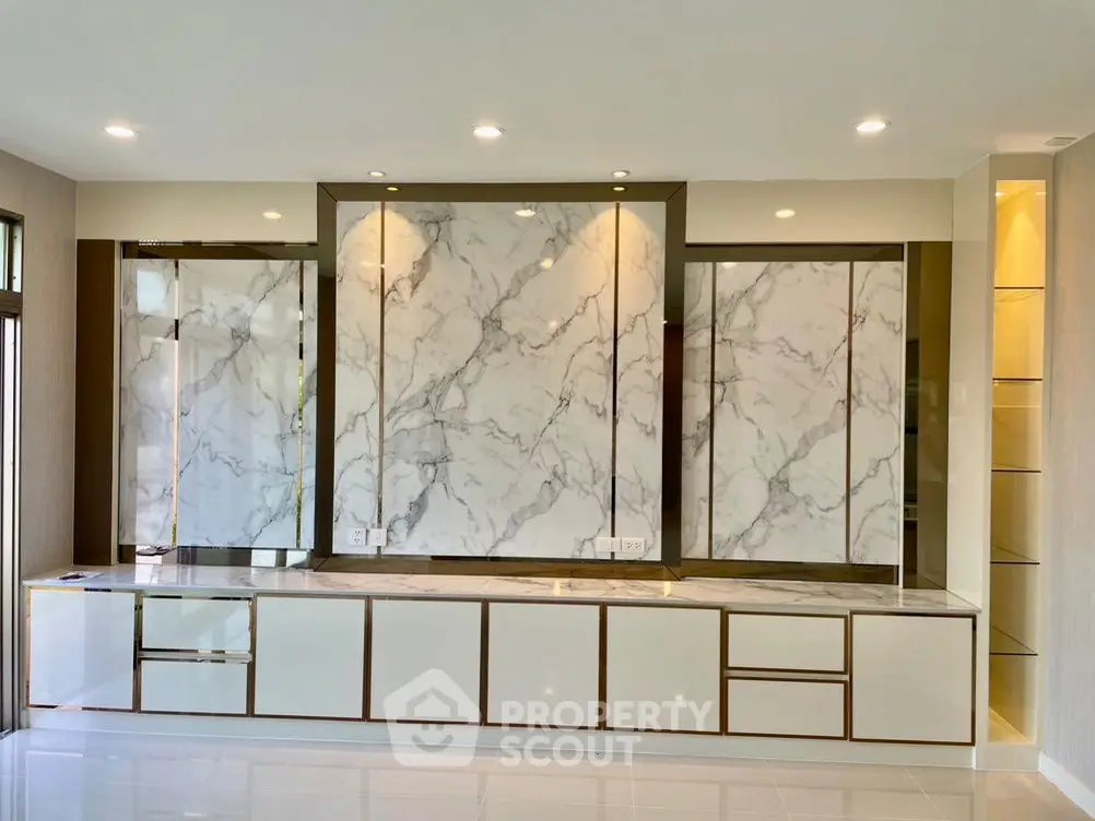 Luxurious modern living room with marble wall panels and sleek cabinetry.