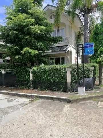 Charming two-story house with lush greenery and palm trees, perfect for serene living.