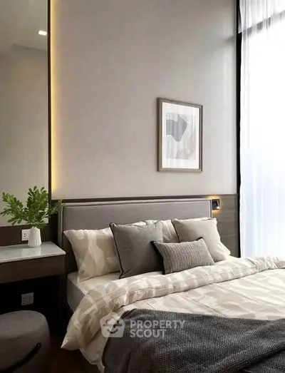 Modern bedroom with stylish decor and natural light, featuring a cozy bed and elegant wall art.