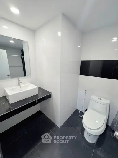Modern bathroom with sleek black and white design, featuring a stylish sink and toilet.