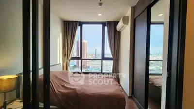 Modern bedroom with large window offering city view and stylish decor.