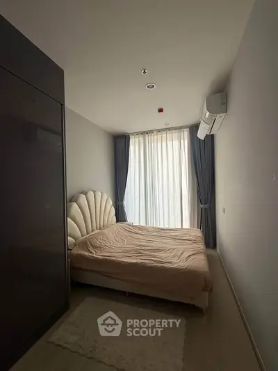 Cozy bedroom with modern design and natural light from large window.