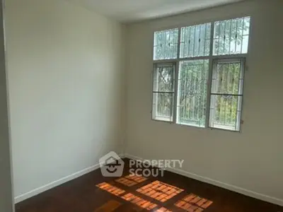 Bright empty room with large window and wooden floor, perfect for customization.