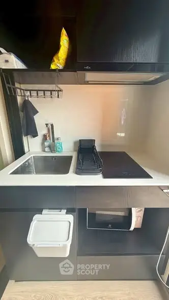 Modern compact kitchen with sleek black cabinetry and built-in appliances, perfect for urban living.