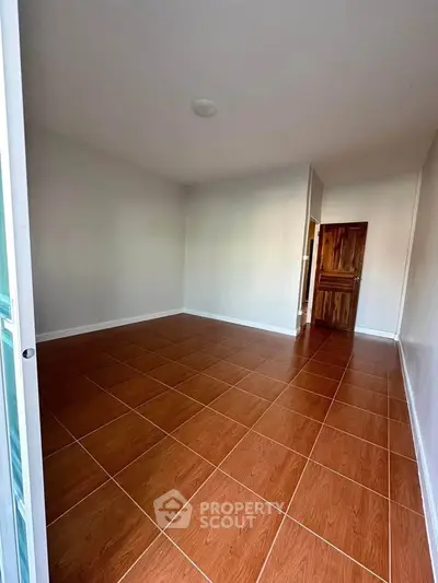 Spacious empty room with wooden flooring and white walls, perfect for customization.