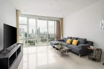 Modern living room with city view, sleek furniture, and large windows in a high-rise apartment.
