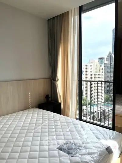 Modern bedroom with city view and large window in high-rise apartment