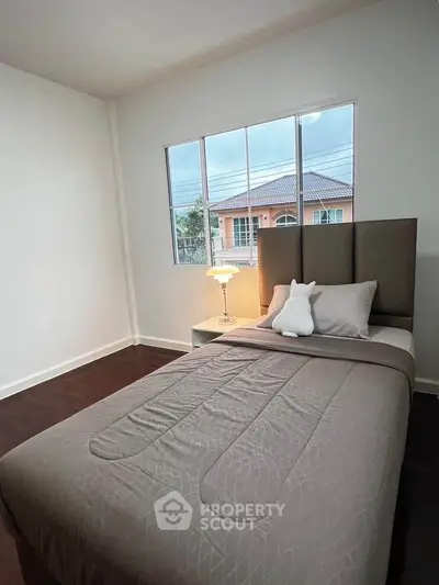 Cozy bedroom with single bed and large window offering natural light