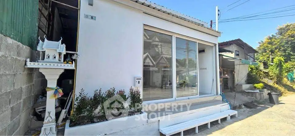 Charming small white house with sliding glass doors and a quaint garden.