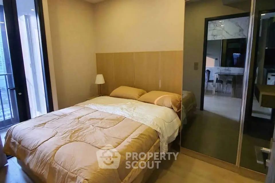 Cozy bedroom with modern decor and mirrored wardrobe in a stylish apartment.