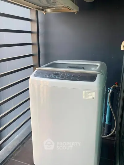 Modern washing machine on a balcony with sleek railing design.