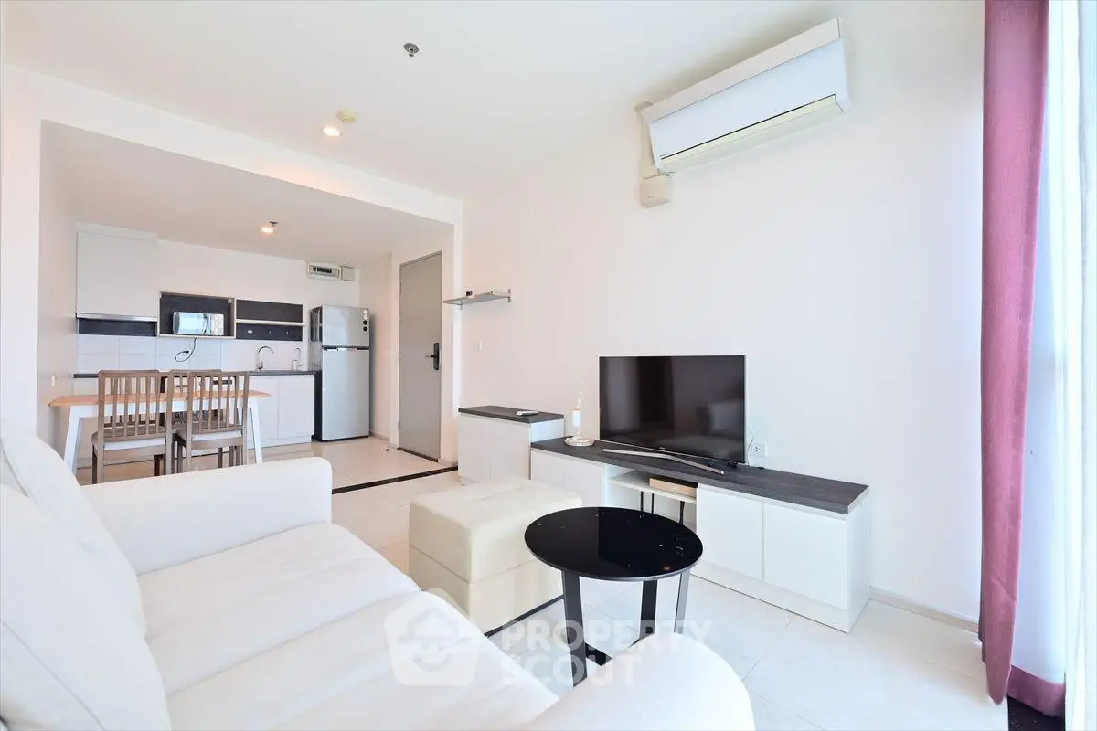 Modern open-plan living room with kitchen, featuring sleek furniture and natural light.