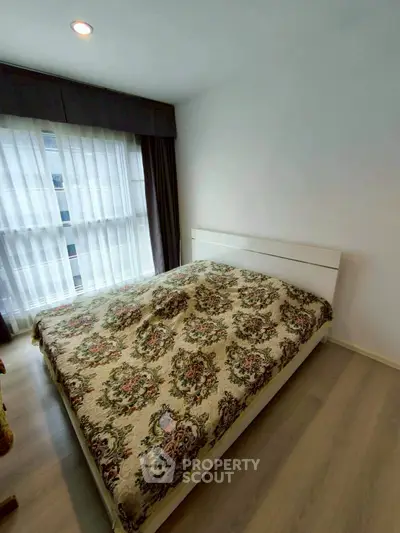 Cozy bedroom with large window and elegant floral bedding in modern apartment.