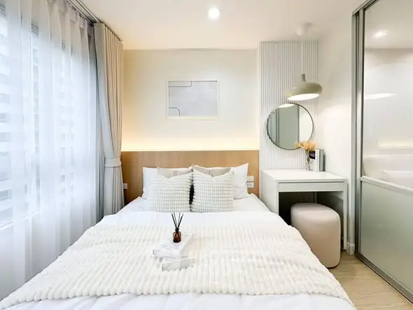 Modern bedroom with cozy decor and natural light, featuring a stylish bed and elegant furnishings.