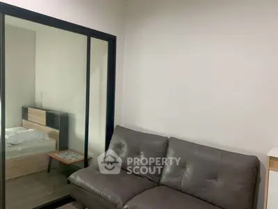Modern apartment with cozy living room and bedroom separated by glass sliding door.