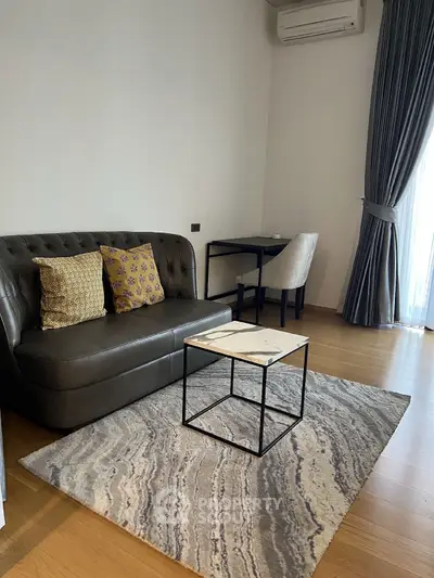 Modern living room with stylish sofa, elegant rug, and natural light from large window.