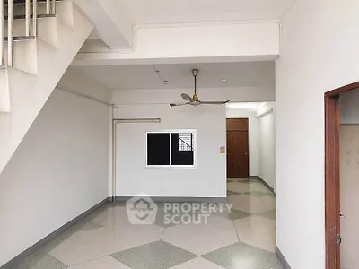 Spacious interior with modern flooring and ceiling fan, featuring a staircase and hallway.