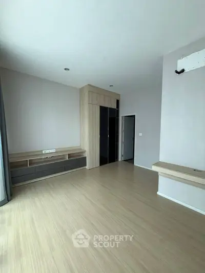 Spacious modern living room with wooden flooring and built-in storage solutions.