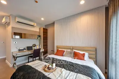 Modern bedroom with stylish decor and workspace, featuring a cozy bed and elegant lighting.