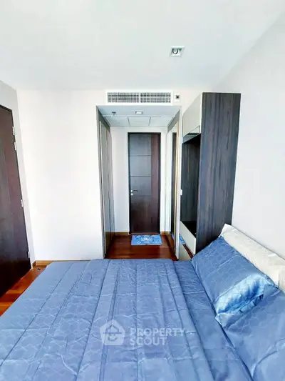 Modern bedroom with sleek design and wooden flooring in a high-rise apartment.