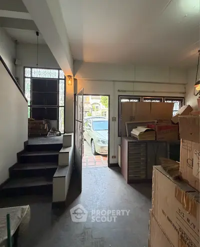 Spacious entryway with staircase and view of parked car outside, ideal for storage or renovation.