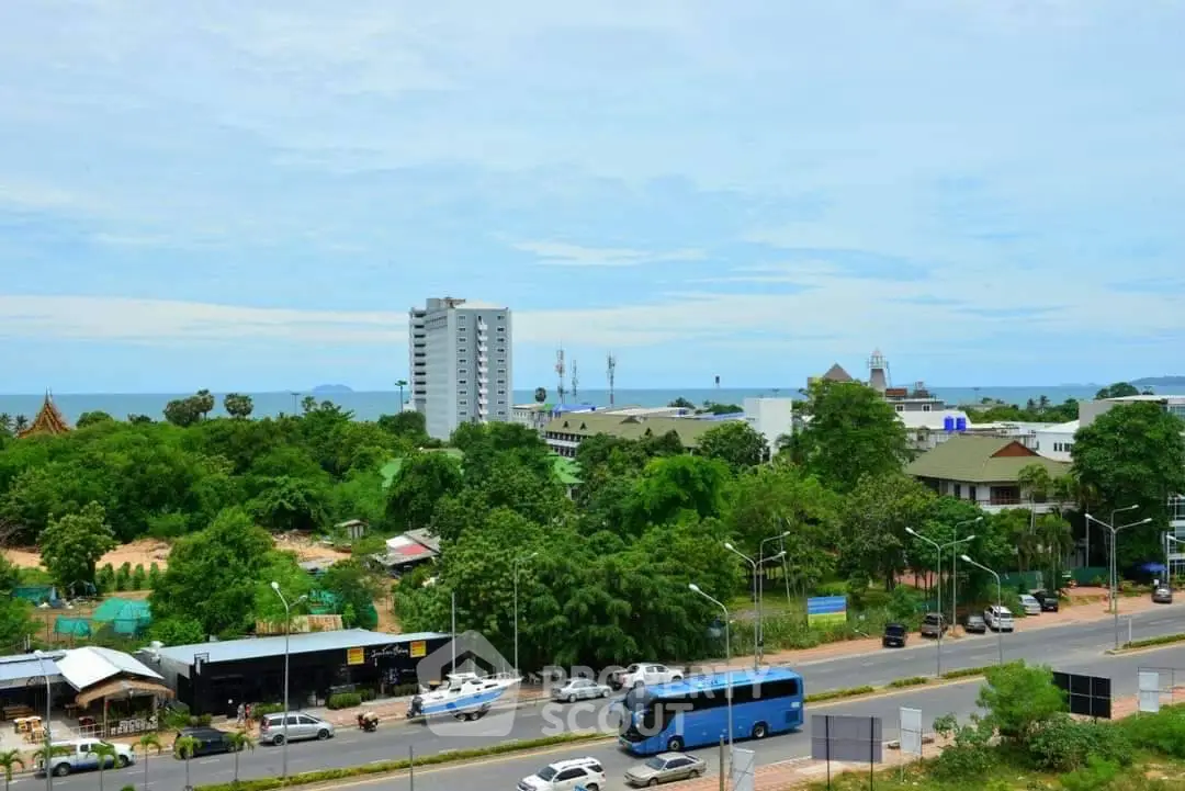 Scenic view of urban landscape with lush greenery and distant ocean horizon.