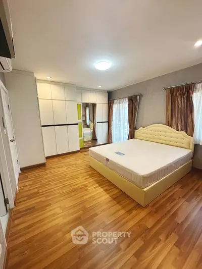 Spacious bedroom with wooden flooring and elegant furnishings