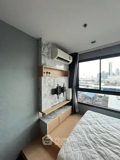 Modern bedroom with city view, featuring stylish decor and large window for natural light.