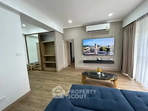 Modern living room with stylish decor and large TV, featuring a cozy blue sofa and elegant coffee table.