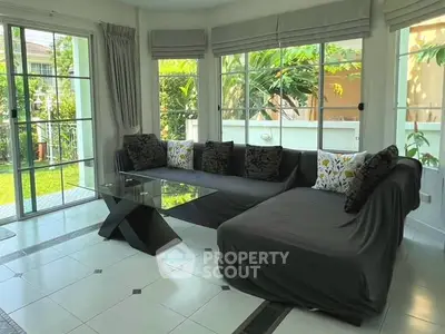 Spacious living room with modern glass table and garden view, perfect for relaxation and entertaining.