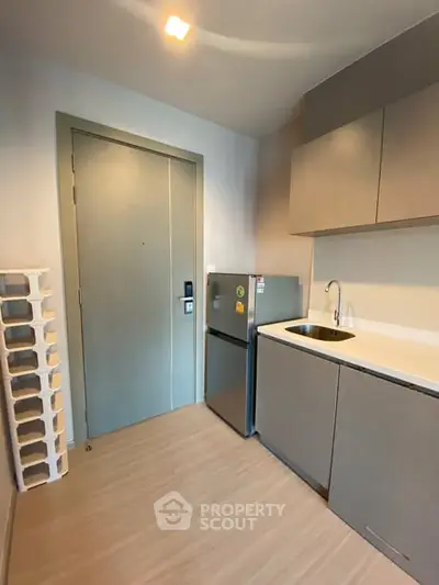 Modern compact kitchen with sleek cabinetry and mini fridge in a stylish apartment.