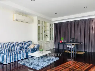 Spacious living room with elegant decor and natural light, featuring a cozy striped sofa and modern desk area.