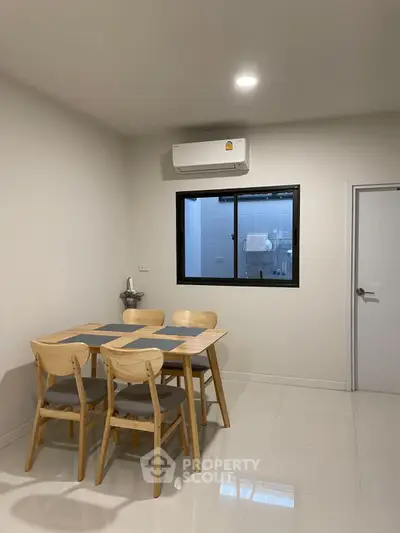 Modern dining area with sleek table and chairs, air conditioning, and minimalist decor.