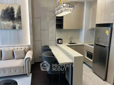 Modern open-layout kitchen with sleek cabinetry and cozy living area, featuring elegant lighting and contemporary decor.