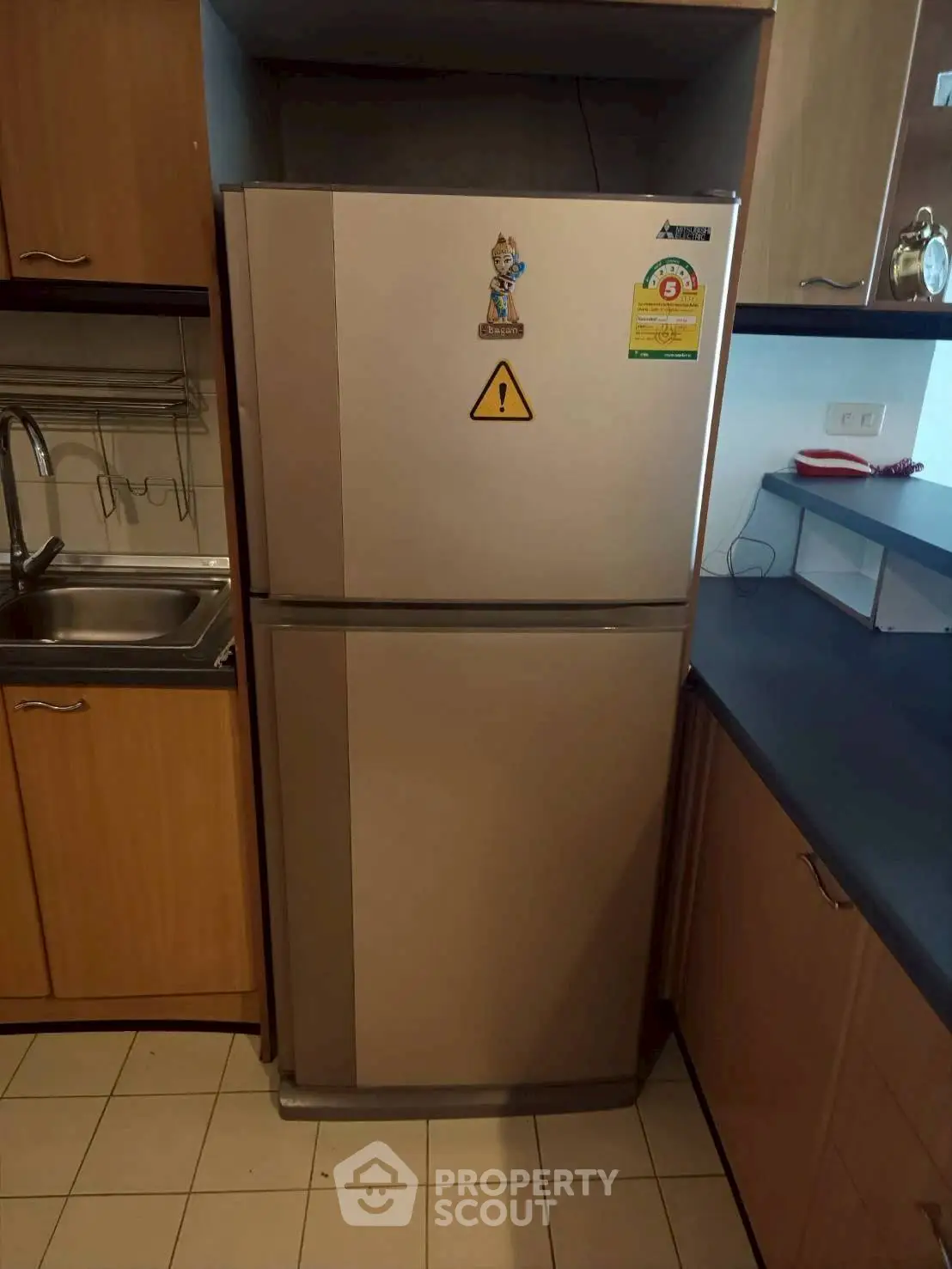 Modern kitchen with stainless steel refrigerator and wooden cabinetry.