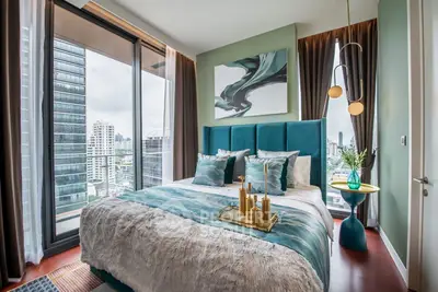Luxurious bedroom with city view, elegant decor, and floor-to-ceiling windows in modern apartment.