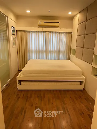 Spacious bedroom with wooden flooring and modern decor, featuring a comfortable bed and ambient lighting.