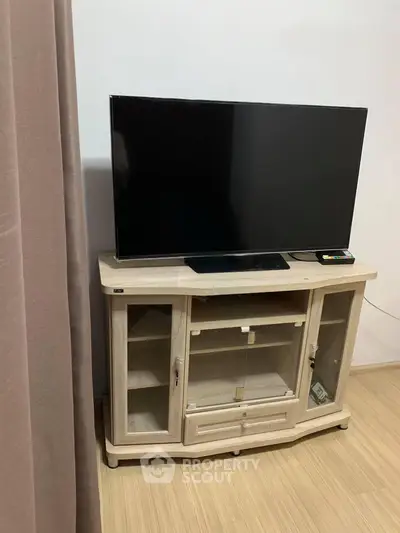 Modern living room with sleek TV stand and flat-screen television on wooden flooring.