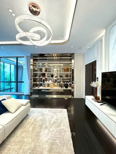 Luxurious living room with modern chandelier and elegant decor, featuring a large window with a serene view.