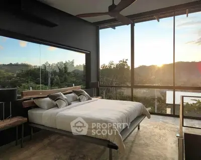 Luxurious bedroom with panoramic window offering stunning sunset views over lush greenery.