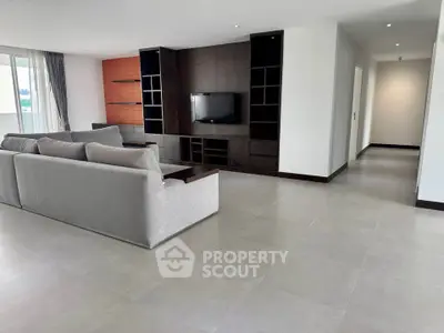 Spacious modern living room with sleek entertainment center and large sofa, perfect for relaxation.