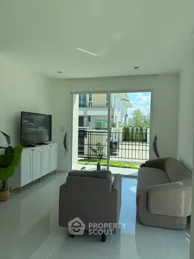 Modern living room with sleek furniture and large window offering natural light and garden view.