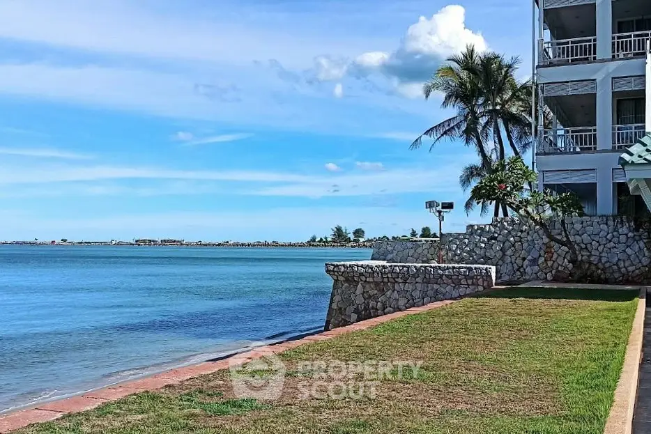 Stunning oceanfront property with lush lawn and palm trees, perfect for serene coastal living.