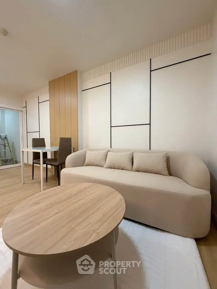 Modern living room with stylish beige sofa and wooden coffee table, featuring elegant wall paneling and dining area.
