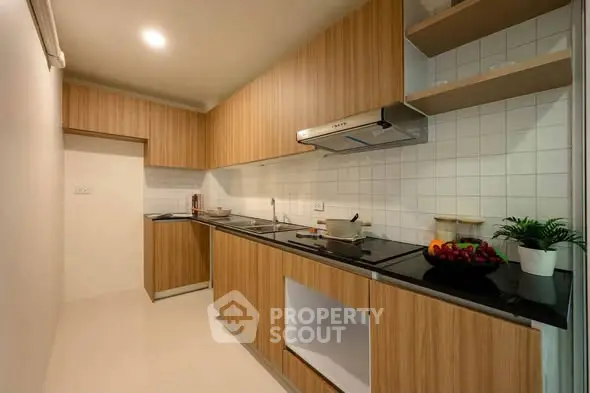 Modern kitchen with sleek wooden cabinetry and built-in appliances, perfect for culinary enthusiasts.