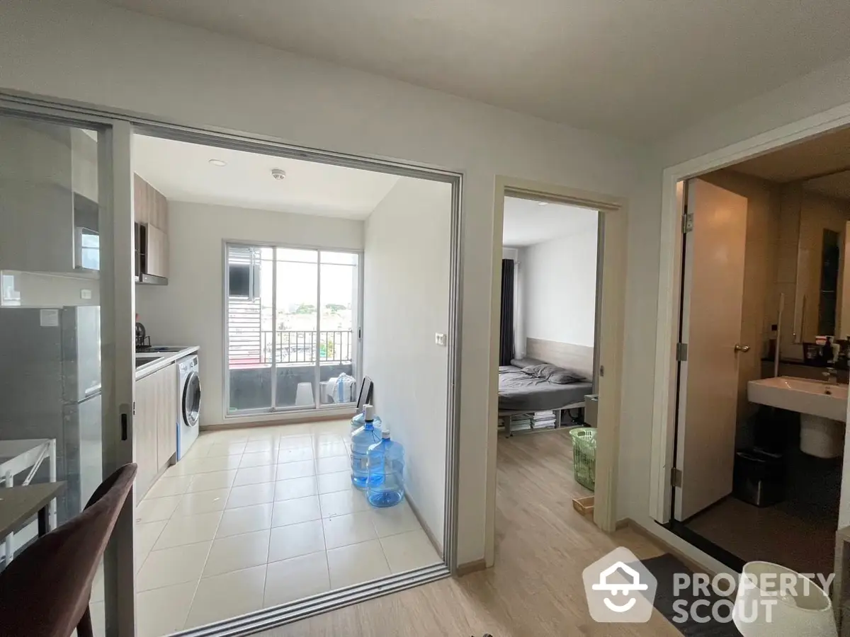 Spacious apartment interior with open layout connecting a modern kitchen to a cozy living area and a sunlit balcony, perfect for urban living.