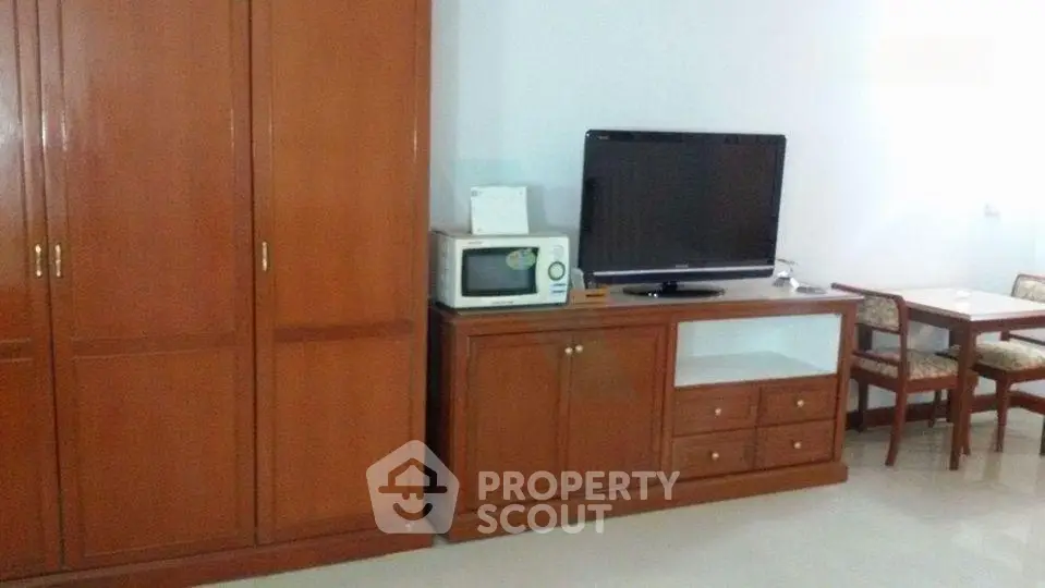 Spacious living area with wooden furniture and modern appliances for comfortable living.