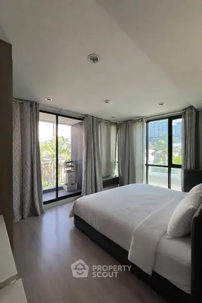 Spacious bedroom with large windows and balcony access, offering a serene view.