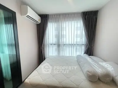 Cozy bedroom with large window and air conditioning in modern apartment.
